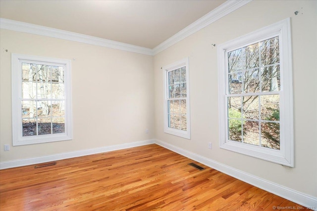 empty room featuring crown molding, baseboards, and visible vents