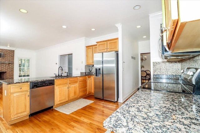 kitchen featuring light wood-style flooring, a sink, stainless steel appliances, a peninsula, and crown molding