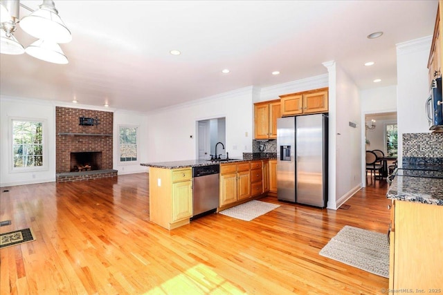 kitchen with crown molding, decorative backsplash, a peninsula, stainless steel appliances, and a sink