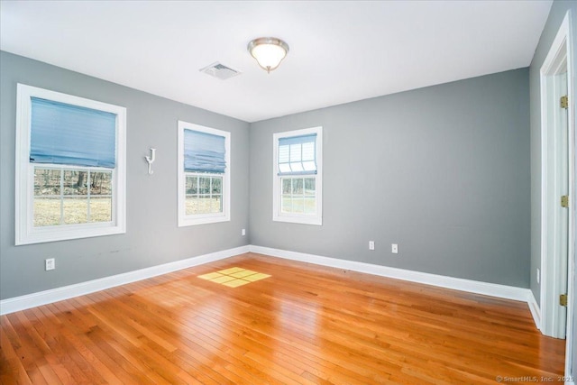 empty room featuring visible vents, light wood-style flooring, and baseboards