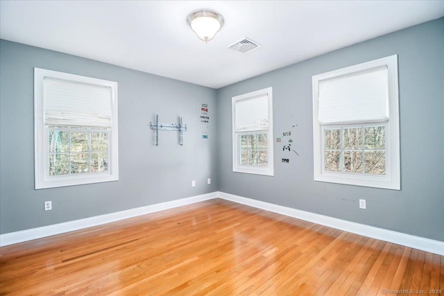 spare room featuring light wood-style flooring, visible vents, and baseboards