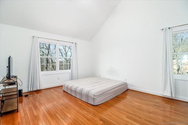 bedroom with lofted ceiling, baseboards, and light wood-type flooring