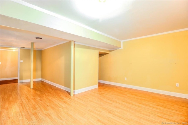 finished below grade area featuring light wood-type flooring, crown molding, and baseboards
