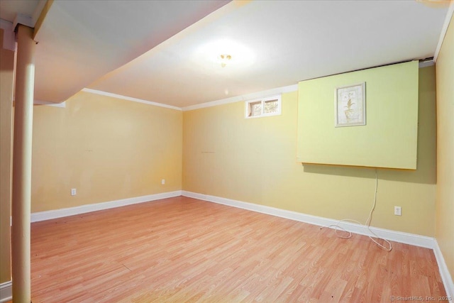 basement featuring wood finished floors, baseboards, and ornamental molding