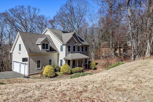 view of front of property with aphalt driveway, an attached garage, a front yard, and a shingled roof