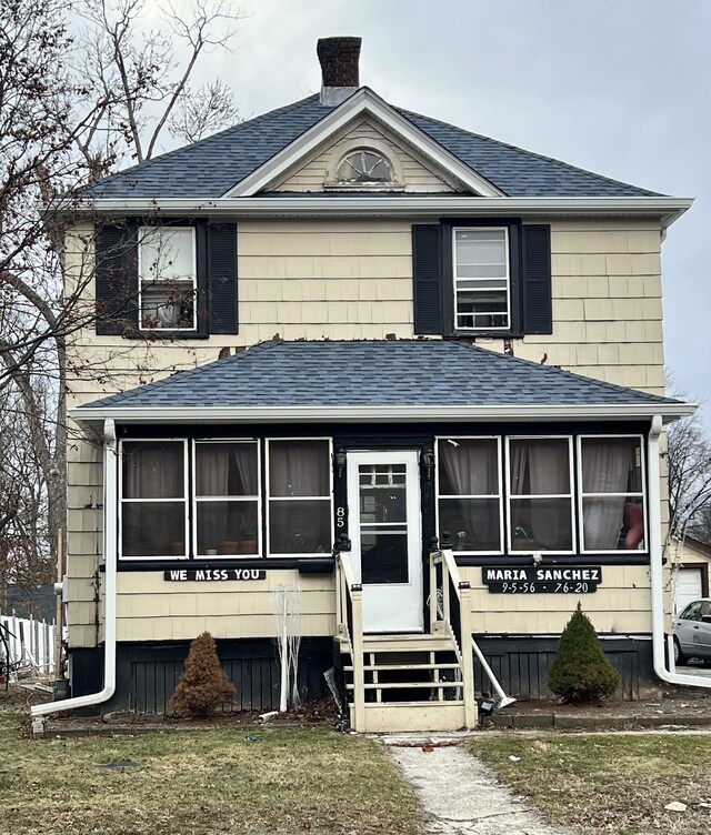 view of front of property with a sunroom, roof with shingles, a chimney, and entry steps