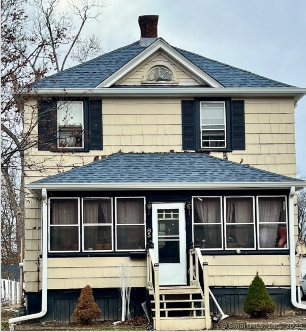 view of front of house with a chimney, a sunroom, roof with shingles, and entry steps