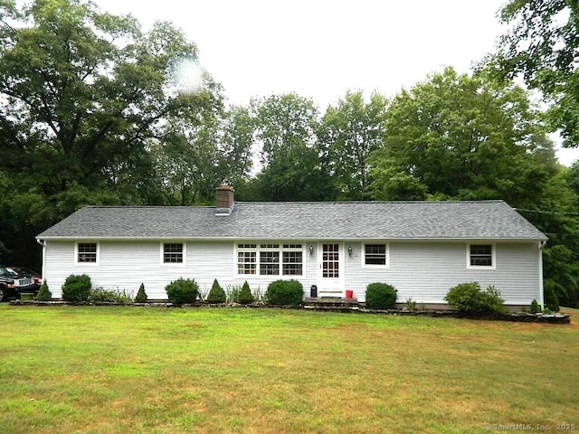 view of front facade featuring entry steps, a chimney, and a front yard