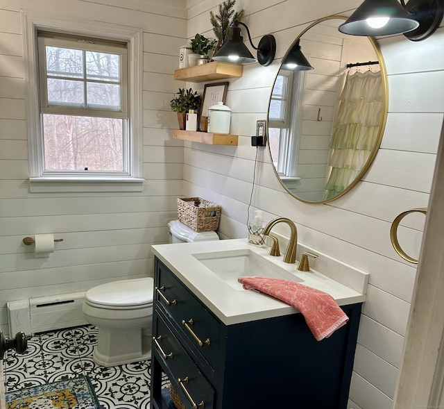 full bath featuring a baseboard radiator, toilet, vanity, and wood walls