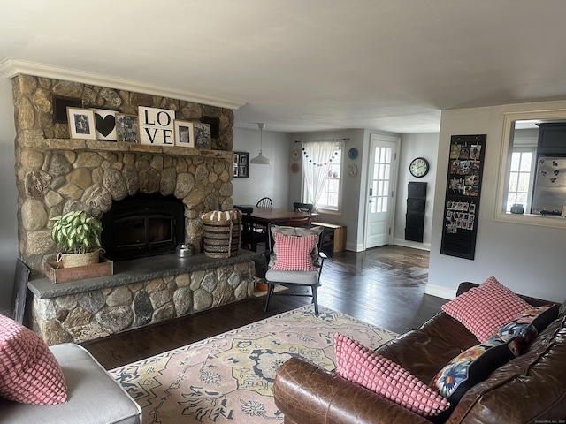 living room with a stone fireplace, baseboards, and wood finished floors