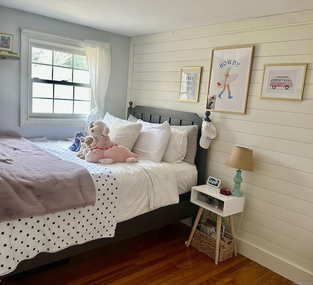 bedroom featuring wood walls and dark wood-style floors