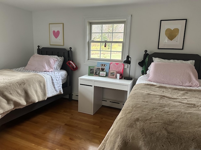 bedroom with a baseboard heating unit and wood finished floors