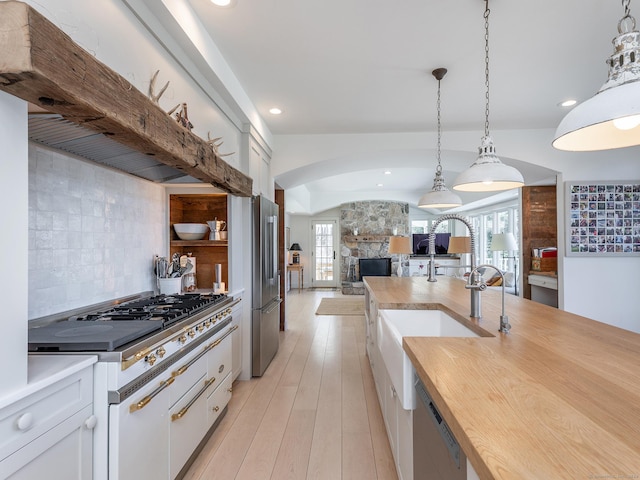 kitchen with a fireplace, decorative backsplash, light wood-style floors, high quality appliances, and open floor plan