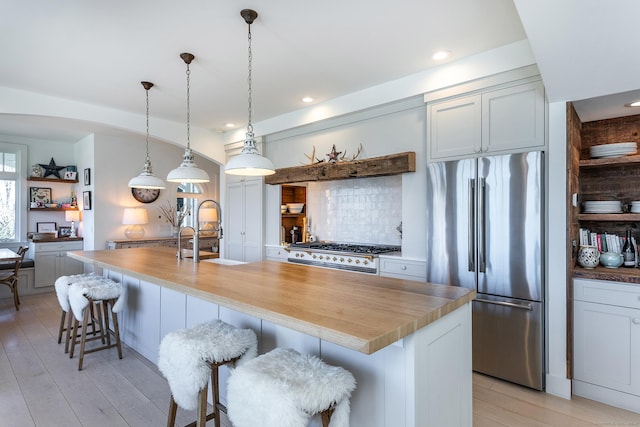 kitchen with a kitchen bar, a sink, tasteful backsplash, range, and high end refrigerator