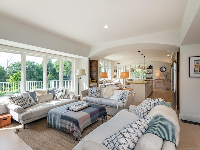 living area with arched walkways, recessed lighting, baseboards, and light wood-style floors
