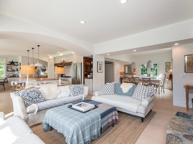 living room featuring arched walkways, recessed lighting, and light wood finished floors