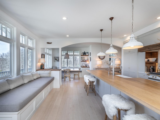 kitchen featuring a breakfast bar area, a sink, hanging light fixtures, light wood-style floors, and open floor plan