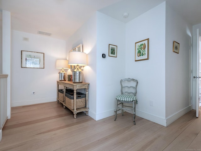corridor with visible vents, baseboards, and wood finished floors