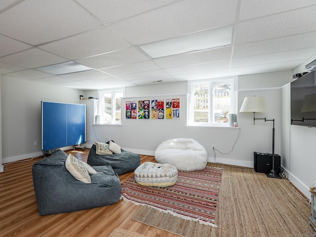 living room with a drop ceiling, baseboards, and wood finished floors