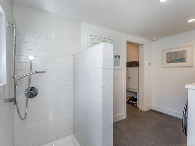 bathroom with recessed lighting, baseboards, vanity, and a tile shower