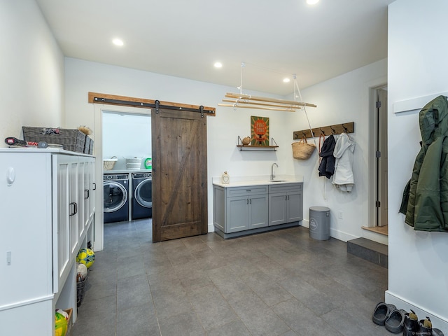 washroom featuring washing machine and dryer, a barn door, laundry area, recessed lighting, and a sink