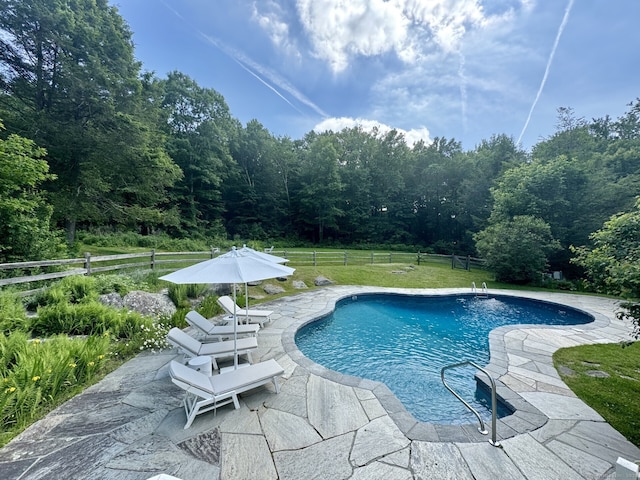 outdoor pool featuring a yard, fence, and a patio area