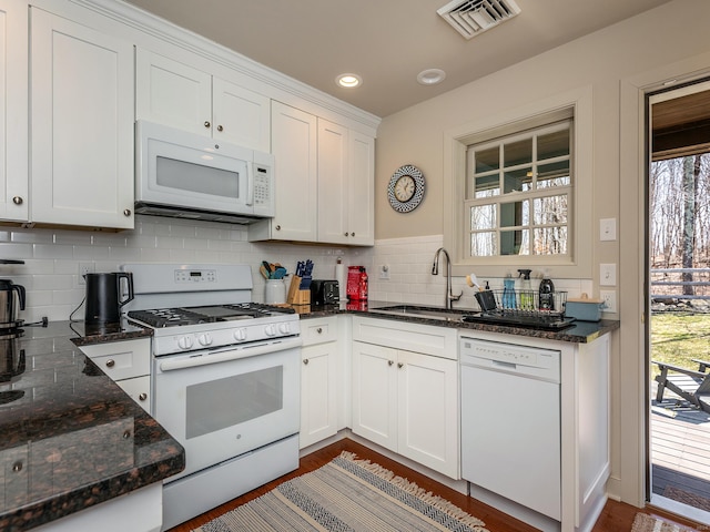 kitchen with tasteful backsplash, visible vents, white appliances, white cabinetry, and a sink