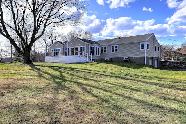 back of house featuring a wooden deck, a sunroom, and a lawn