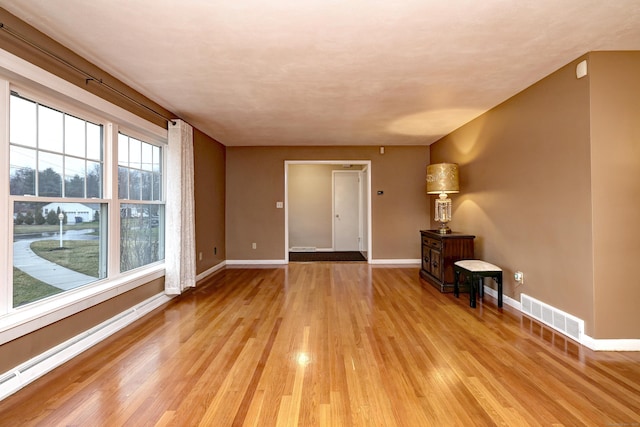 unfurnished room with baseboards, visible vents, a baseboard heating unit, and light wood-type flooring