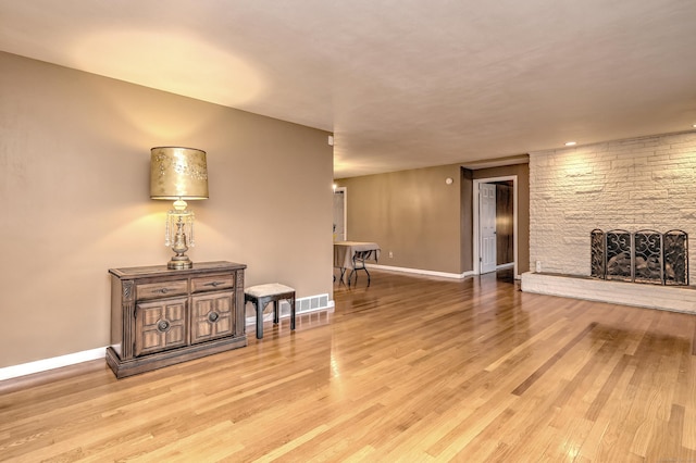 interior space with light wood finished floors, baseboards, and a stone fireplace