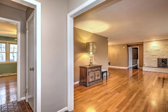 hallway featuring baseboards, visible vents, and wood finished floors