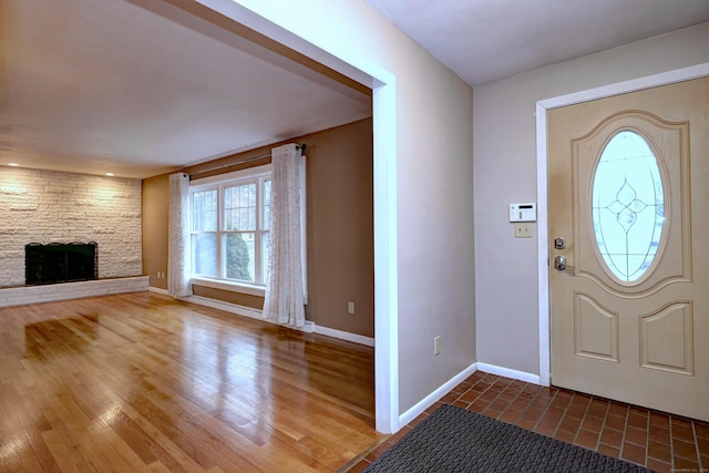 entryway with a stone fireplace, baseboards, and wood finished floors