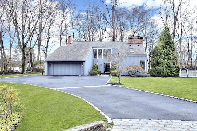 mid-century home featuring roof with shingles, a chimney, driveway, an attached garage, and a front lawn