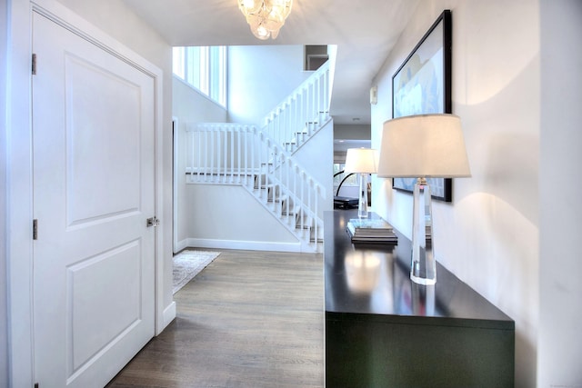 foyer entrance featuring stairway, baseboards, an inviting chandelier, and wood finished floors