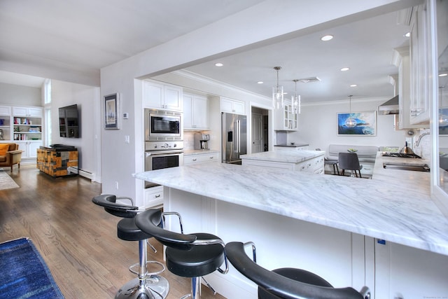 kitchen featuring light stone countertops, a peninsula, white cabinets, appliances with stainless steel finishes, and a sink