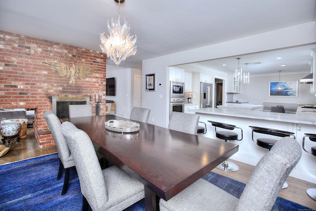 dining area featuring ornamental molding, an inviting chandelier, dark wood finished floors, and a brick fireplace