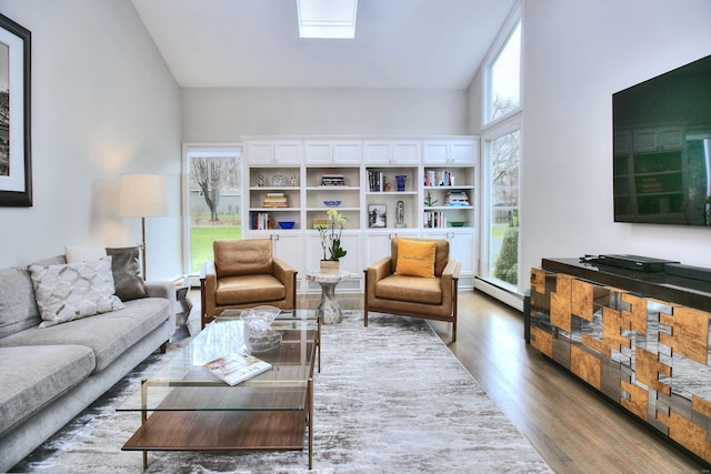 living room featuring a skylight, a baseboard heating unit, and wood finished floors