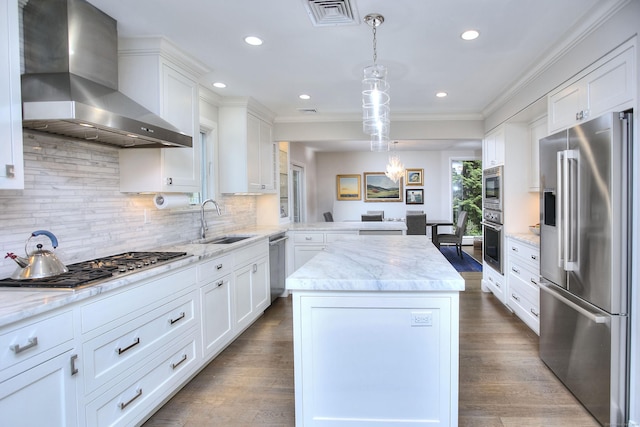 kitchen with a center island, visible vents, wall chimney exhaust hood, stainless steel appliances, and a sink
