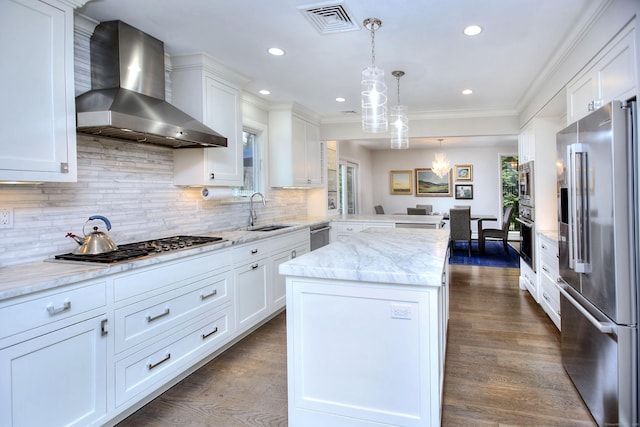 kitchen with a peninsula, wall chimney range hood, visible vents, a sink, and stainless steel appliances