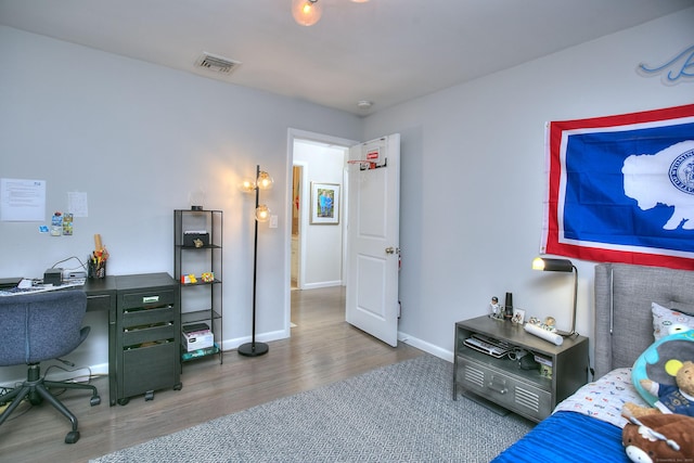 bedroom with visible vents, baseboards, and wood finished floors