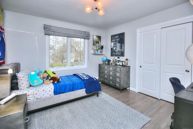 bedroom with a closet, an inviting chandelier, and wood finished floors