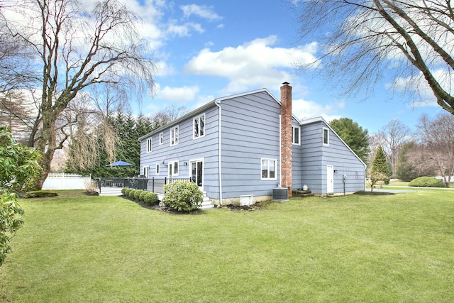 view of property exterior featuring fence, a yard, central air condition unit, and a chimney