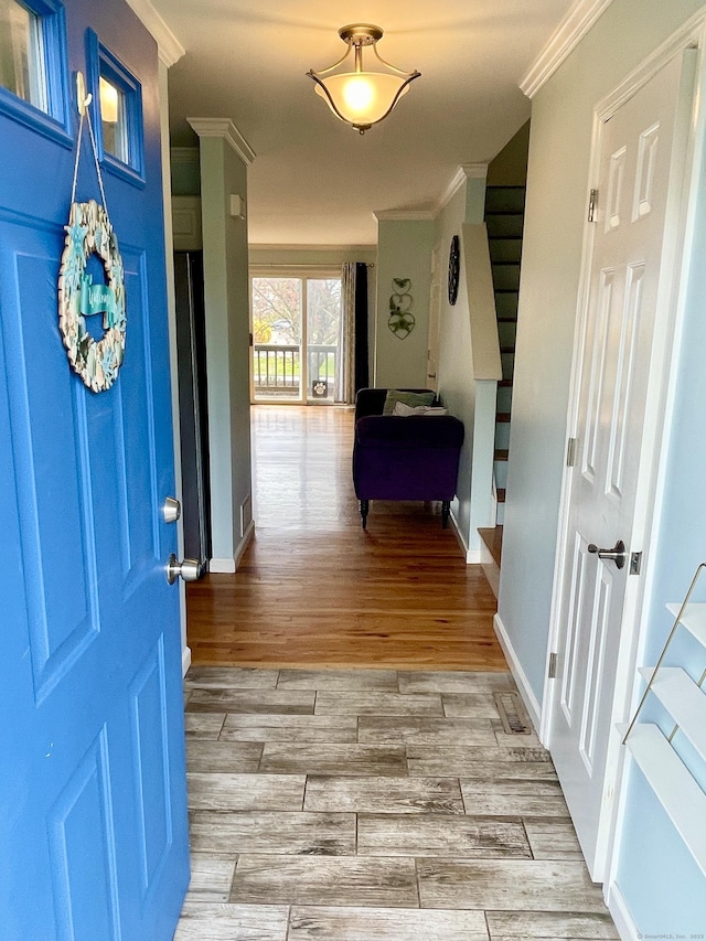 foyer entrance with stairway, light wood-style flooring, ornamental molding, and baseboards
