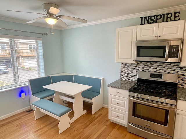 kitchen featuring decorative backsplash, ceiling fan, white cabinetry, ornamental molding, and appliances with stainless steel finishes