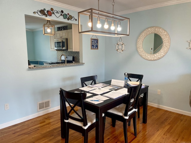 dining room featuring visible vents, wood finished floors, and crown molding