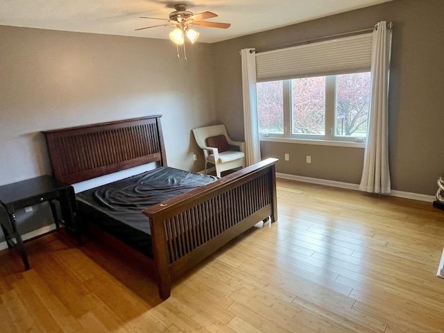bedroom featuring a ceiling fan, light wood-style flooring, and baseboards