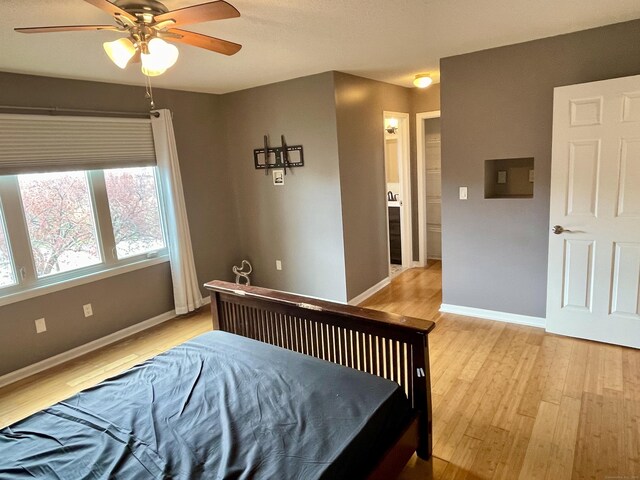 bedroom with ceiling fan, baseboards, and light wood-type flooring