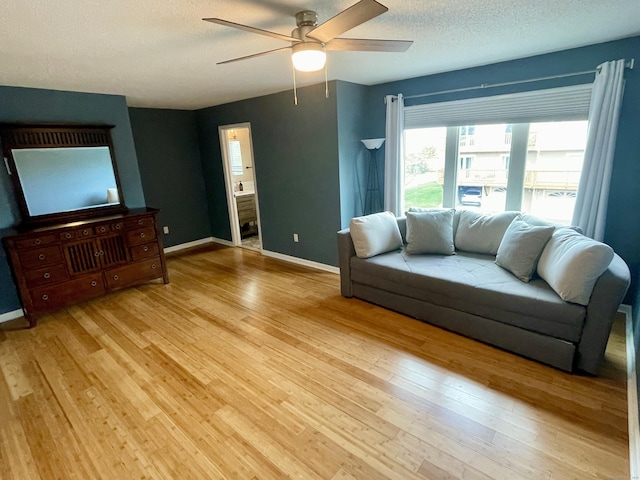 living room featuring baseboards, ceiling fan, and light wood finished floors