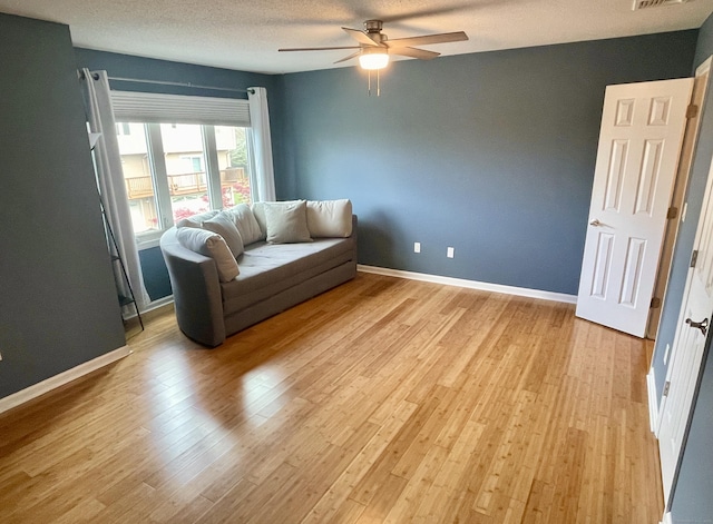 living area with light wood finished floors, ceiling fan, baseboards, and visible vents