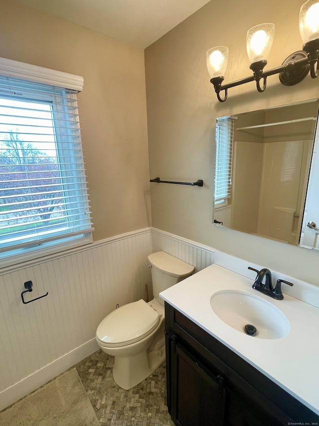 full bathroom with toilet, wainscoting, a shower, and vanity
